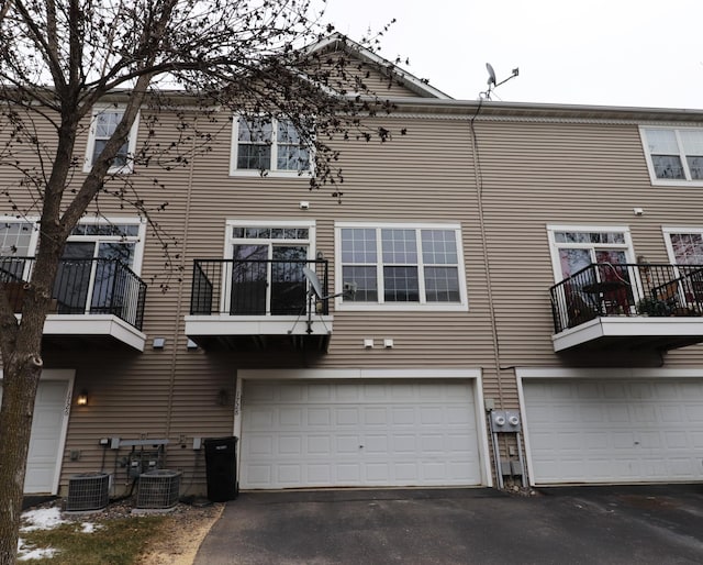 rear view of property with a garage, central air condition unit, and driveway