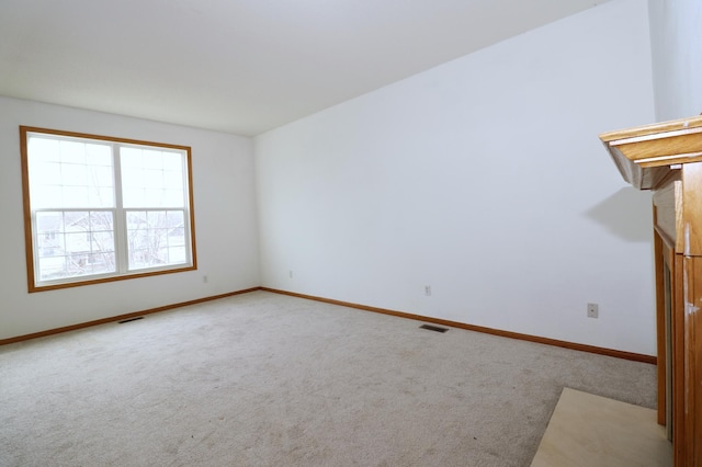 unfurnished room with baseboards, visible vents, and light colored carpet