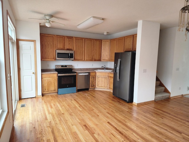 kitchen with light wood-style floors, appliances with stainless steel finishes, light countertops, and a sink