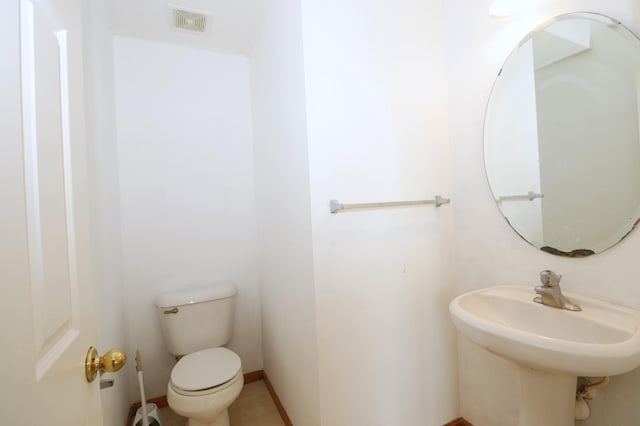 half bathroom featuring toilet, baseboards, and visible vents