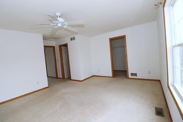 empty room featuring visible vents, light carpet, and baseboards