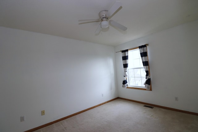 carpeted spare room featuring baseboards, visible vents, and ceiling fan