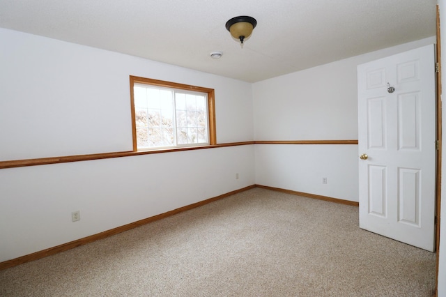 empty room featuring light carpet and baseboards