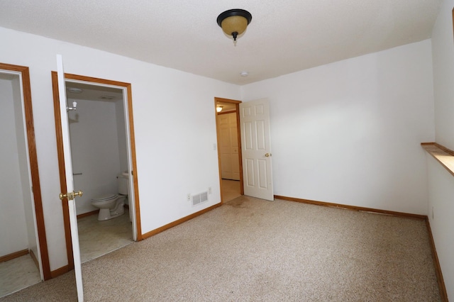 unfurnished bedroom with carpet floors, visible vents, connected bathroom, and baseboards