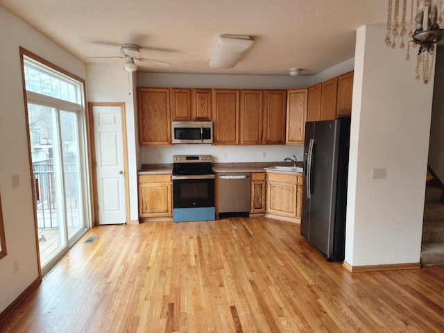 kitchen featuring a sink, light wood finished floors, stainless steel appliances, and light countertops