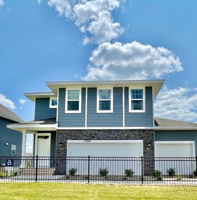 view of front of property featuring a garage, stone siding, a front lawn, and fence