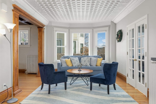 sitting room featuring crown molding, light wood finished floors, an ornate ceiling, and radiator