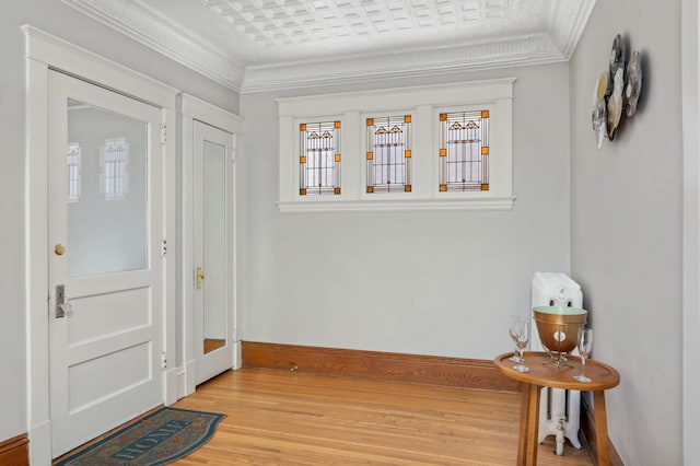 entrance foyer featuring baseboards, light wood-style floors, and crown molding