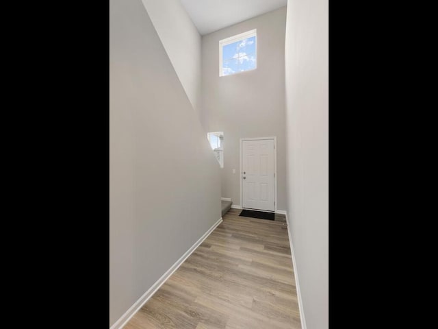 corridor featuring a towering ceiling and light hardwood / wood-style flooring