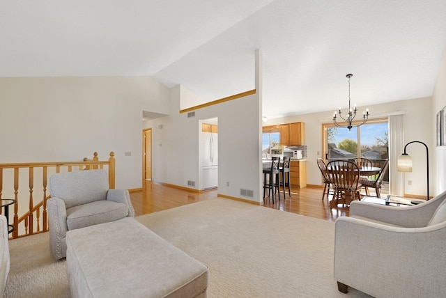 living room featuring light wood-style floors, high vaulted ceiling, visible vents, and a chandelier