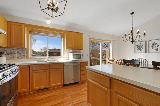 kitchen with a sink, backsplash, a chandelier, and stainless steel appliances