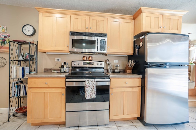 kitchen featuring appliances with stainless steel finishes, light countertops, a textured ceiling, and light brown cabinetry