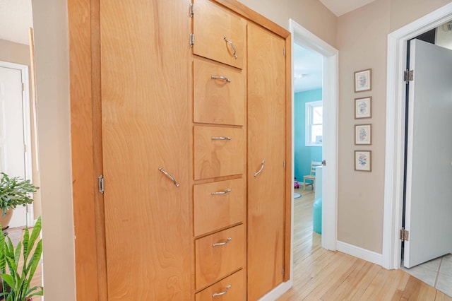 hall featuring light wood-type flooring and baseboards