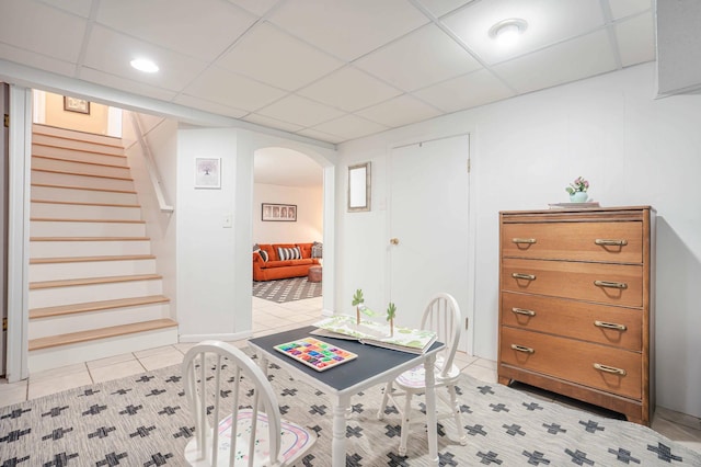 bedroom with arched walkways, a drop ceiling, and light tile patterned floors