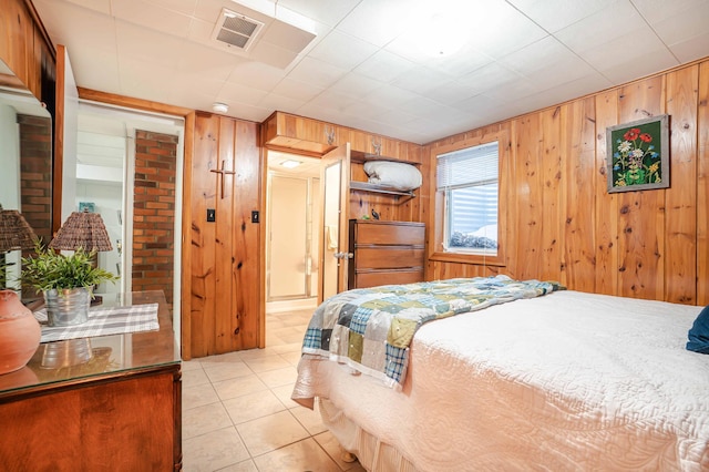 bedroom with wood walls, visible vents, and light tile patterned flooring