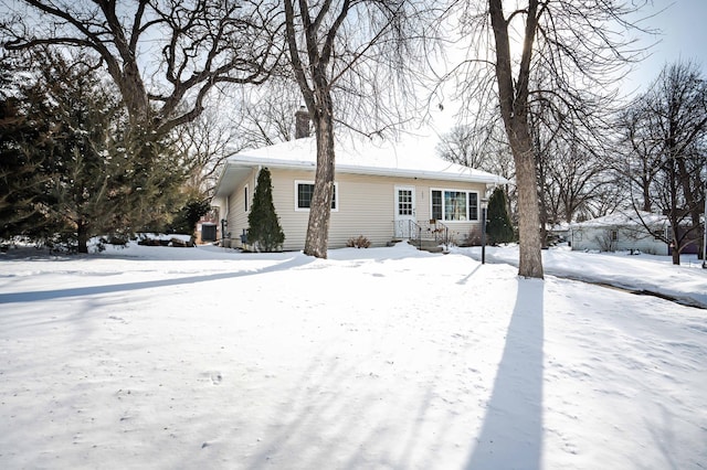 snow covered house featuring a chimney