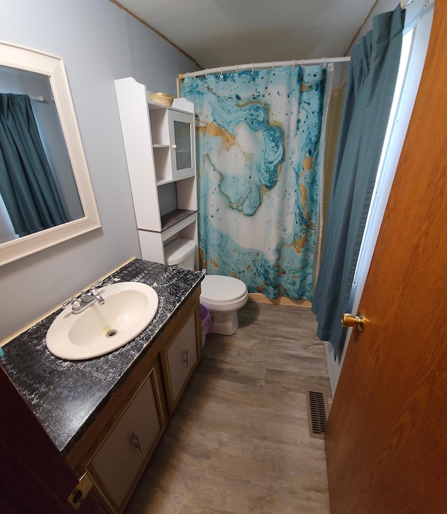 full bathroom with curtained shower, toilet, wood finished floors, vanity, and visible vents