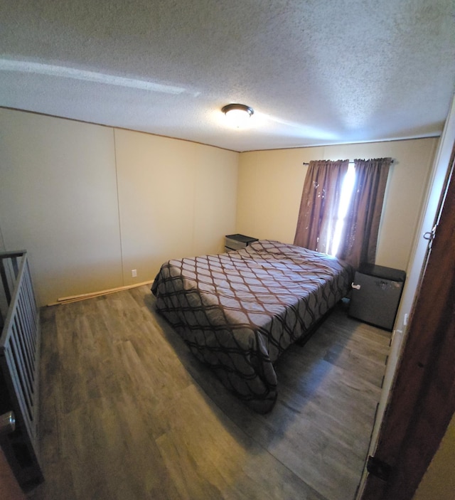 bedroom with a textured ceiling and dark wood-style flooring