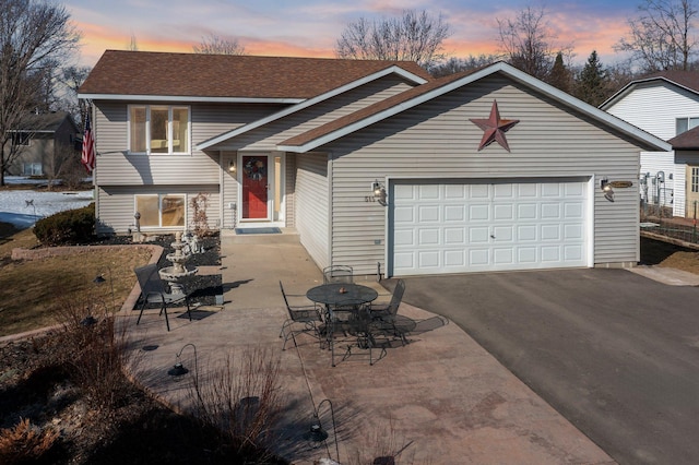 tri-level home featuring driveway, an attached garage, and a shingled roof