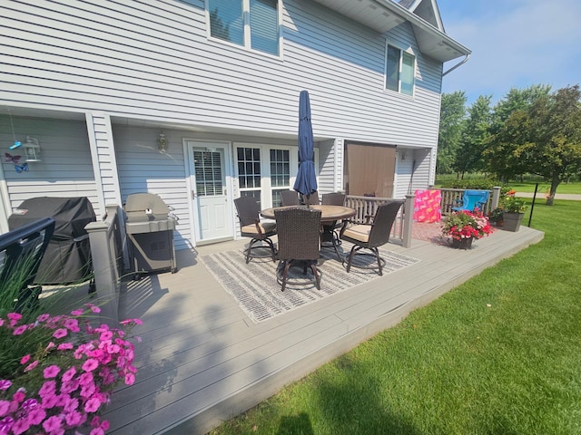 wooden deck featuring outdoor dining area, a lawn, and area for grilling