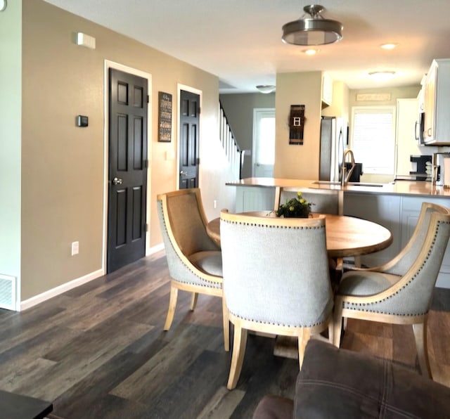 dining room featuring dark wood-style floors, stairway, and baseboards