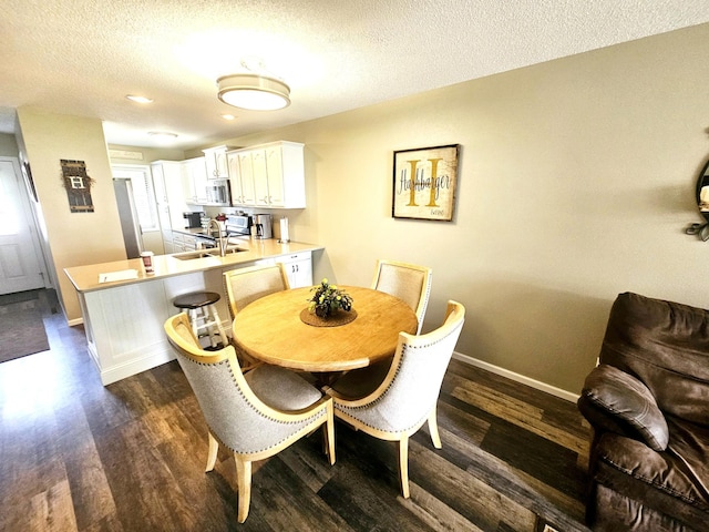 dining area with dark wood-style flooring, a textured ceiling, and baseboards