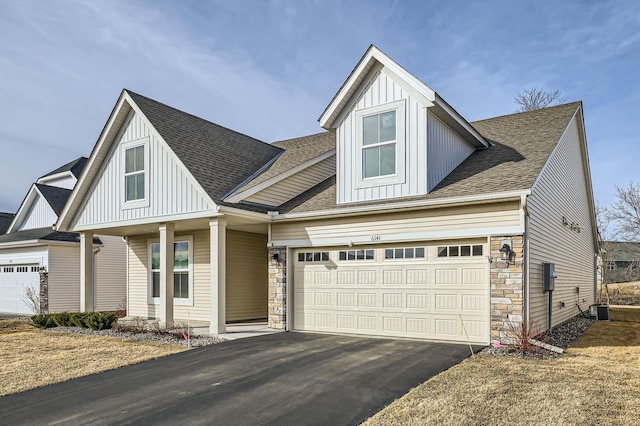 view of front of property with aphalt driveway, stone siding, roof with shingles, board and batten siding, and an attached garage