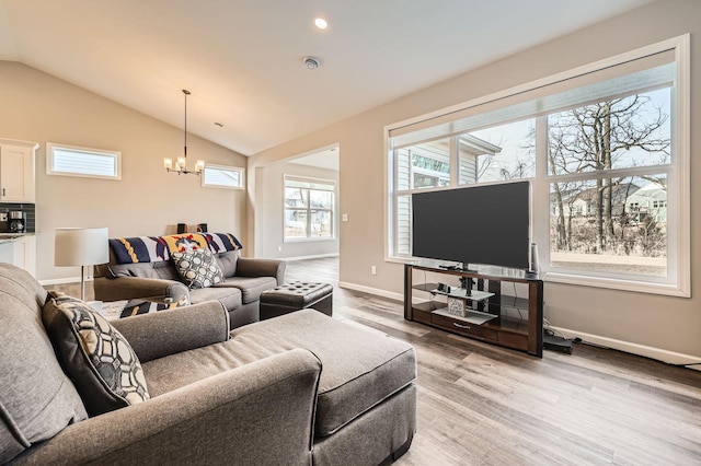 living room with vaulted ceiling, light wood-style flooring, baseboards, and a chandelier