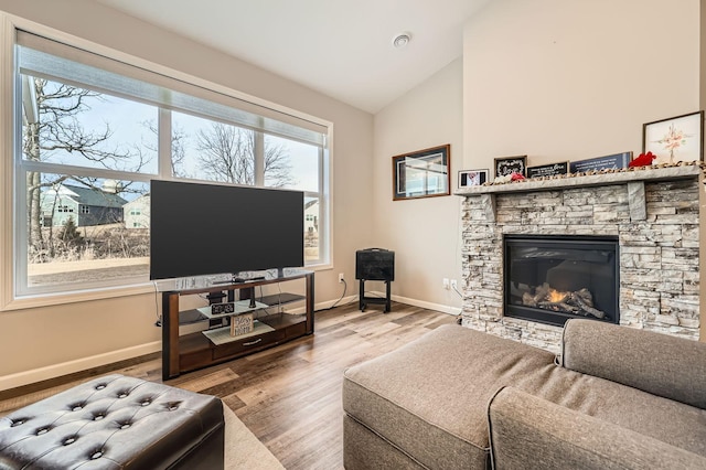 living room featuring a fireplace, vaulted ceiling, wood finished floors, and baseboards