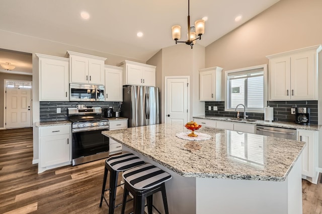 kitchen with white cabinets, stainless steel appliances, lofted ceiling, and a sink