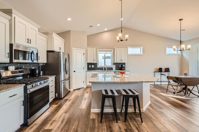 kitchen featuring a notable chandelier, a sink, a center island, white cabinetry, and stainless steel appliances