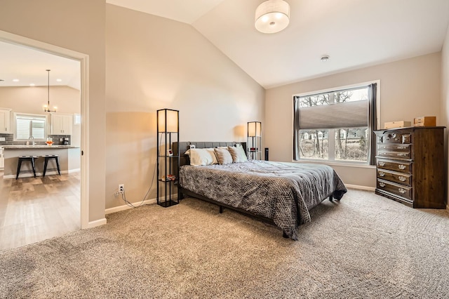 bedroom featuring light colored carpet, high vaulted ceiling, baseboards, and a sink