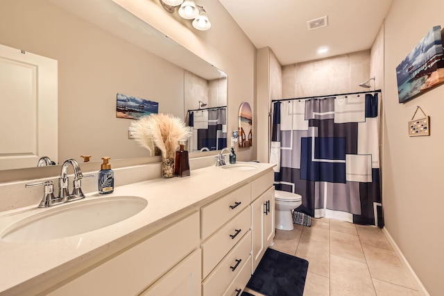 bathroom with a sink, toilet, double vanity, and tile patterned floors