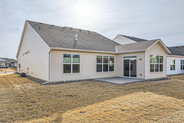 back of property featuring a yard, a patio, roof with shingles, and central AC