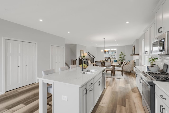 kitchen with stainless steel appliances, light wood-type flooring, a sink, and a breakfast bar area