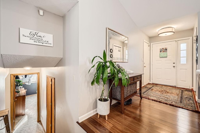 foyer entrance with hardwood / wood-style flooring, baseboards, and lofted ceiling