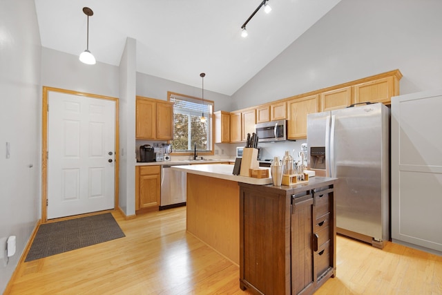 kitchen with light wood-style flooring, a kitchen island, hanging light fixtures, appliances with stainless steel finishes, and light countertops