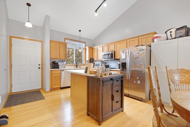 kitchen featuring a center island, decorative light fixtures, light countertops, appliances with stainless steel finishes, and light brown cabinets