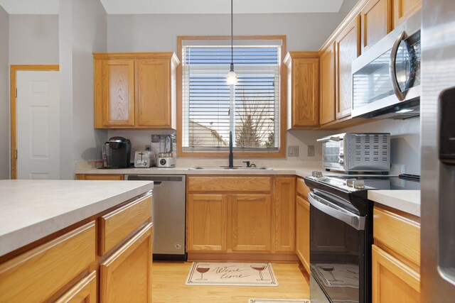 2230 Downing Ave, Shakopee, MN 55379 - kitchen with stainless steel appliances, a sink, light countertops, light wood finished floors, and hanging light fixtures