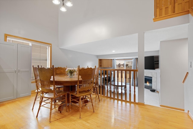 2230 Downing Ave, Shakopee, MN 55379 - dining space featuring light wood finished floors, a towering ceiling, a fireplace, and baseboards