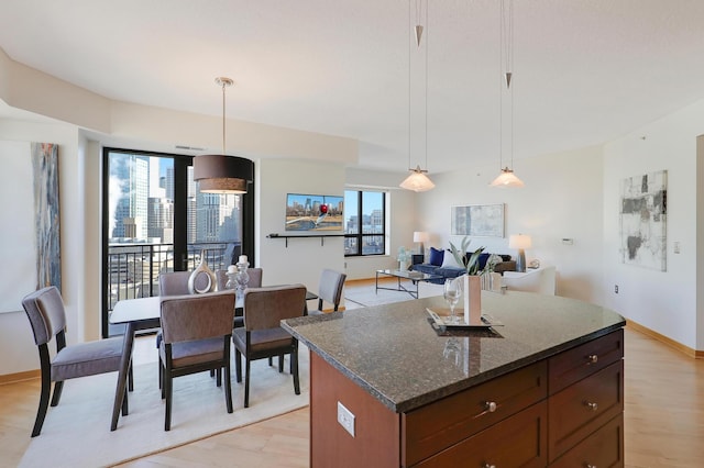 500 Grant St Unit 1302, Minneapolis, MN 55404 - kitchen with light wood-style flooring, dark stone countertops, a kitchen island, and decorative light fixtures
