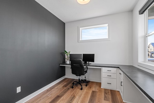 home office featuring baseboards, built in study area, and light wood-style floors