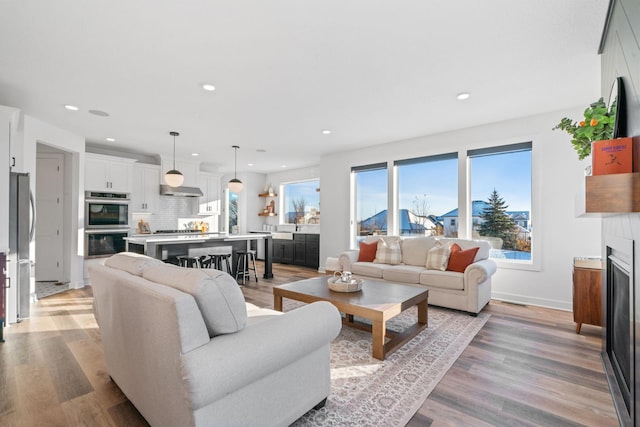 living area featuring light wood-style floors, recessed lighting, a fireplace, and baseboards