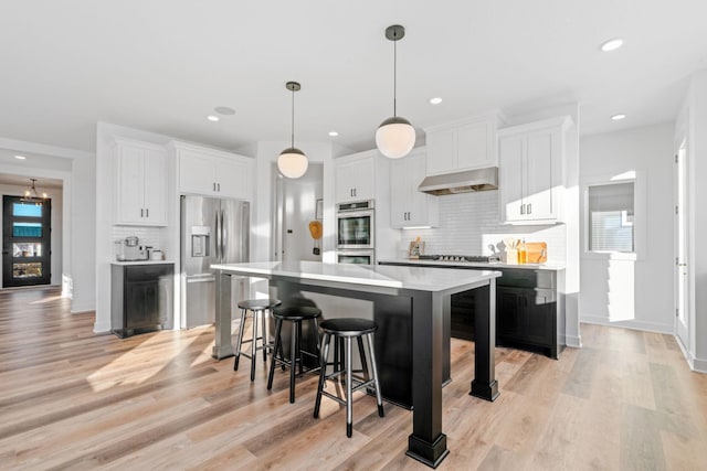 kitchen featuring light countertops, a kitchen island, exhaust hood, and white cabinetry