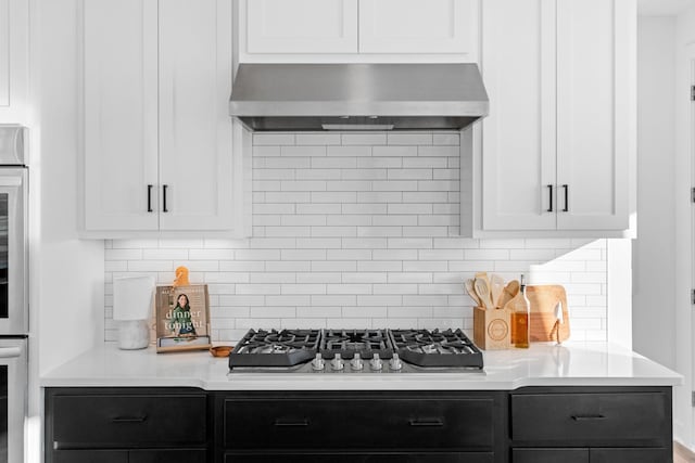 kitchen with light countertops, appliances with stainless steel finishes, extractor fan, and white cabinetry