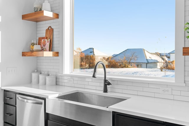 kitchen with a sink, light countertops, stainless steel dishwasher, decorative backsplash, and open shelves