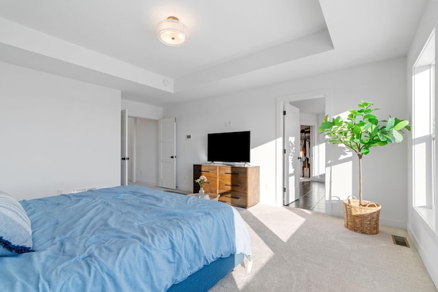 carpeted bedroom featuring a raised ceiling, visible vents, and baseboards