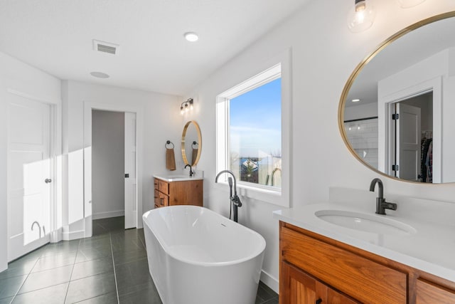 full bathroom featuring visible vents, a sink, tile patterned flooring, a freestanding bath, and two vanities