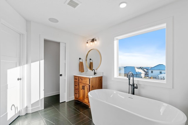 bathroom with vanity, baseboards, visible vents, a soaking tub, and tile patterned floors