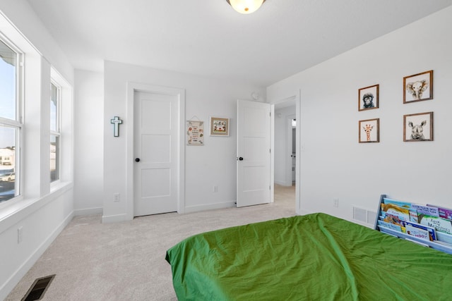 bedroom featuring baseboards, visible vents, and light colored carpet